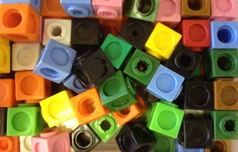 Photo of coloured cubes. There are approximately 40 cubes in a variety of colours. In the photo there appears to be: 4 pink cubes, 7 orange cubes, 3 yellow cubes, 7 blue cubes, 3 cream cubes, 1 red cube, 3 light green cubes, 7 dark green cubes, 3 brown cubes and 8 black cubes.